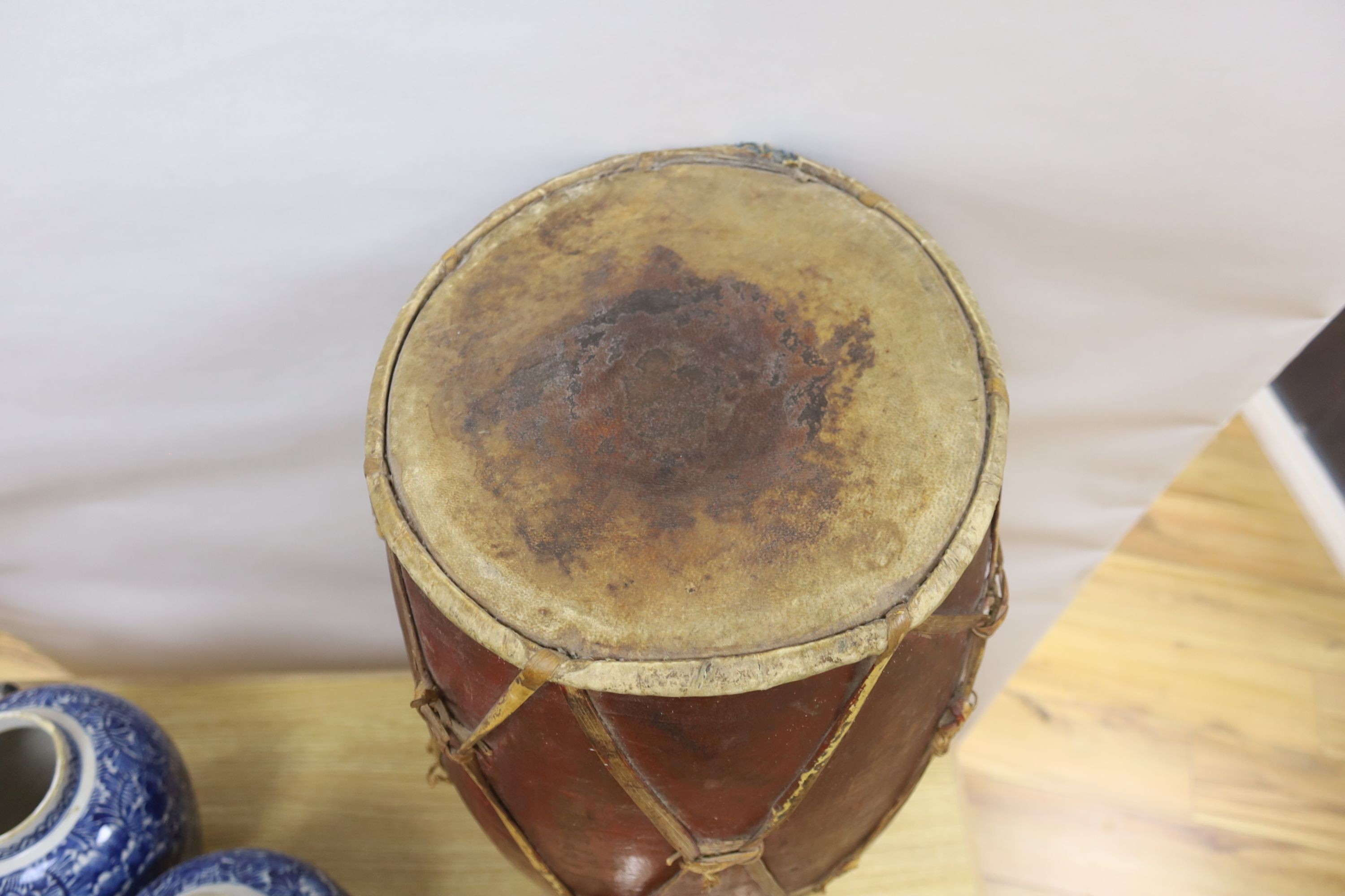 A tall tribal wooden drum, the vellum skins held by bamboo strapping and decorated in red and ochre - 62cm